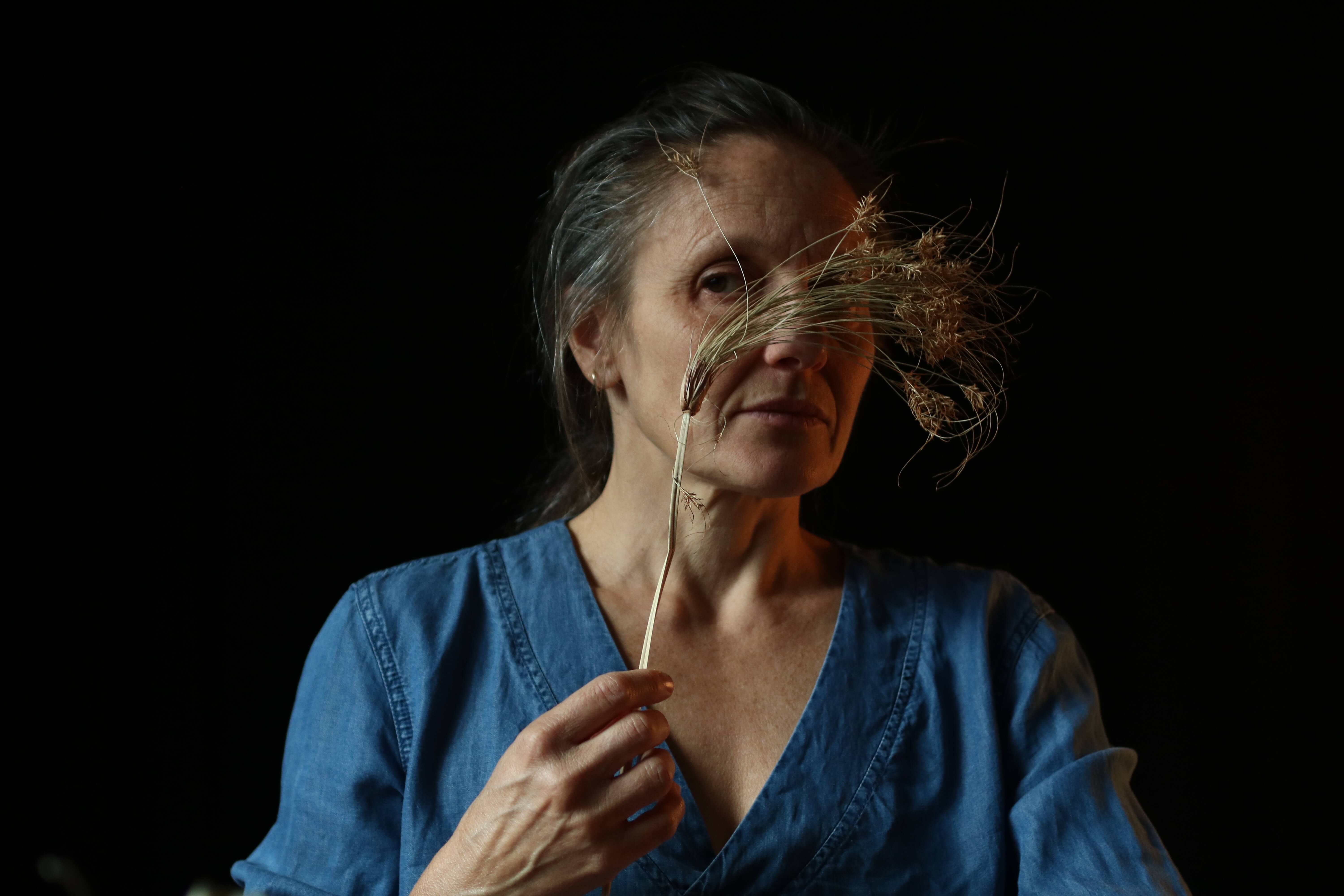 artist holding dried plant infront of face